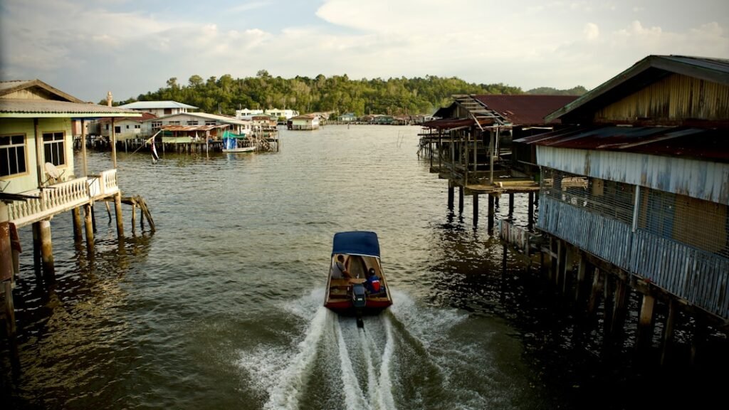 a boat traveling down a river next to a wooden pier